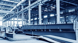 A steel factory floor, stacked with a lot of steel.