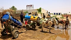 أشخاص يملأون حاويات المياه في نقطة توزيع بسبب انقطاع المياه في الخرطوم، السودان، الأحد 25 مايو 2025.  