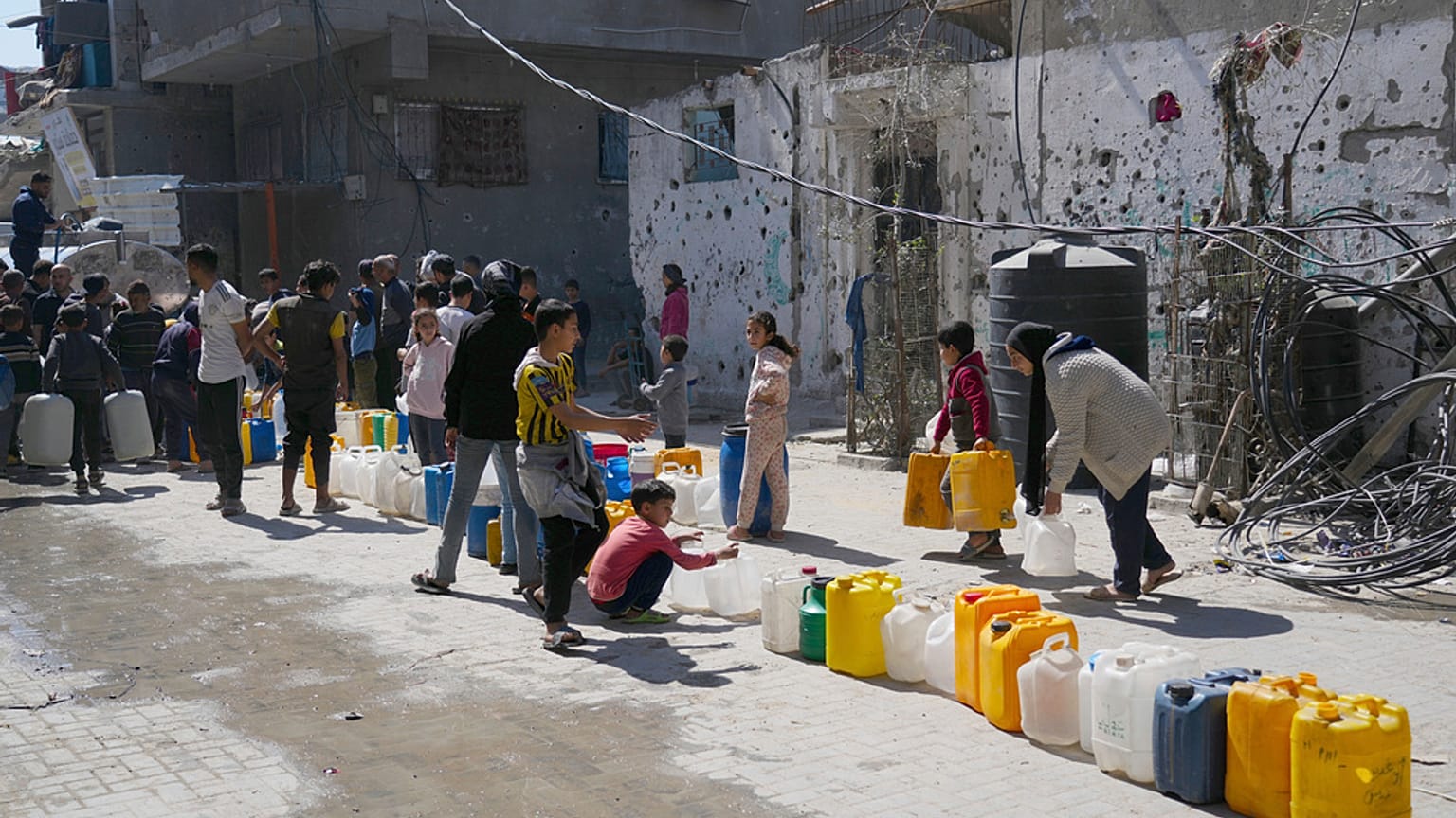 فلسطينيون يصطفون لملء عبوات بالمياه في جباليا، شمال قطاع غزة، يوم الأحد، 16 مارس 2025. 