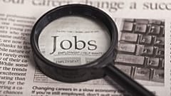 Ein Vergrößerungsglas auf einer Zeitung, das das Wort "Jobs" vergrößert.