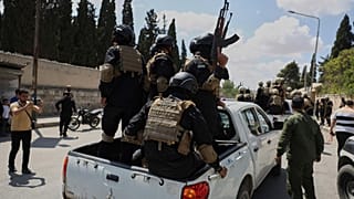 أفراد من قوة أمنية حكومية يركبون في الجزء الخلفي من شاحنة صغيرة أثناء تبادل الأسرى بين السلطات السورية وقوات سوريا الديمقراطية، يوم الاثنين 2 يونيو/حزيران 2025. 