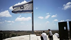 Ein Mann und seine Söhne beobachten von einem Aussichtspunkt in Sderot, Südisrael, am jüdischen Feiertag Schawuot, den Rauch der israelischen Bombardierung