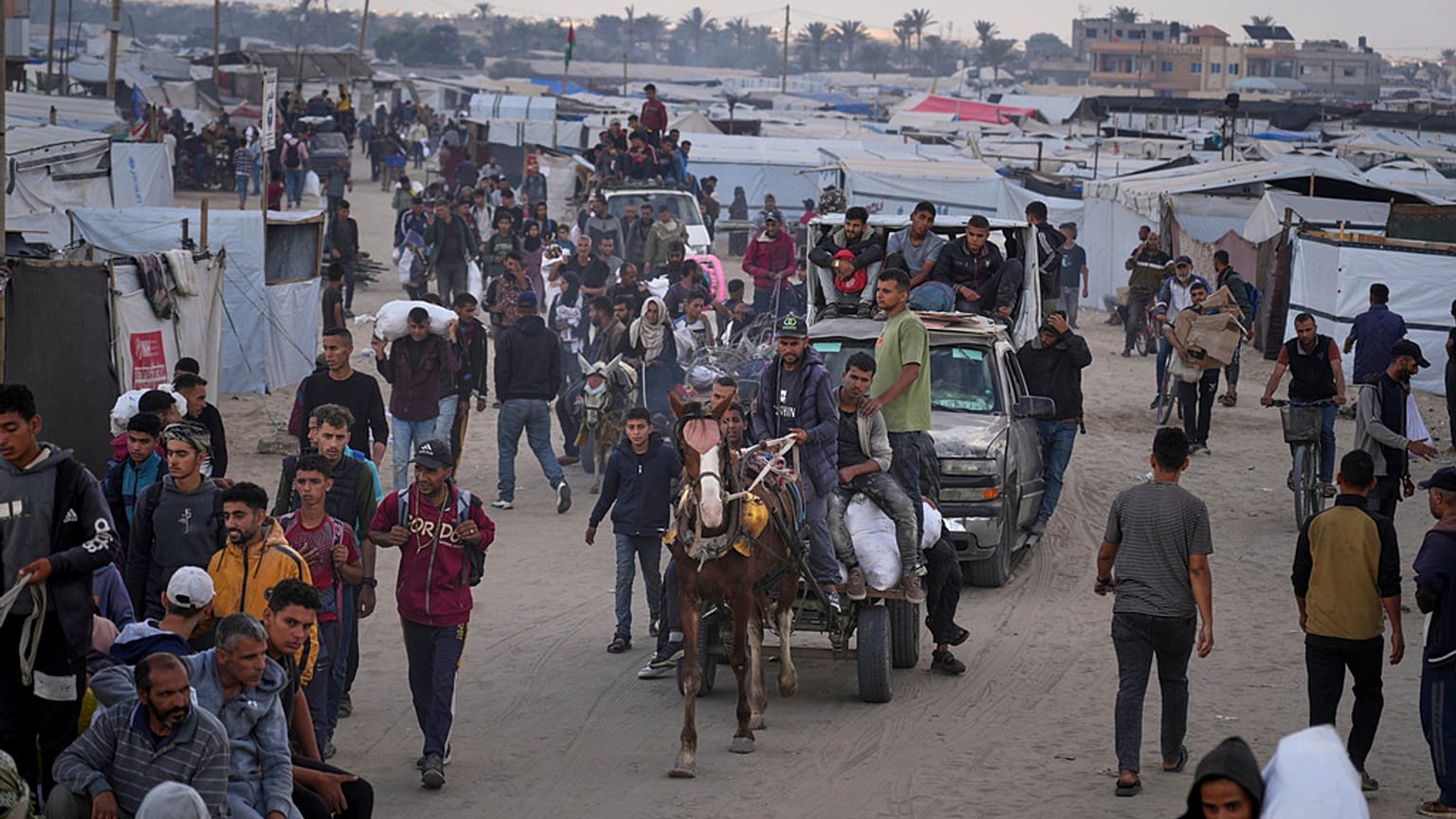 Palestinianos carregam sacos cheios de alimentos e ajuda humanitária fornecidos pela Fundação Humanitária de Gaza, uma organização apoiada pelos EUA e aprovada por Israel