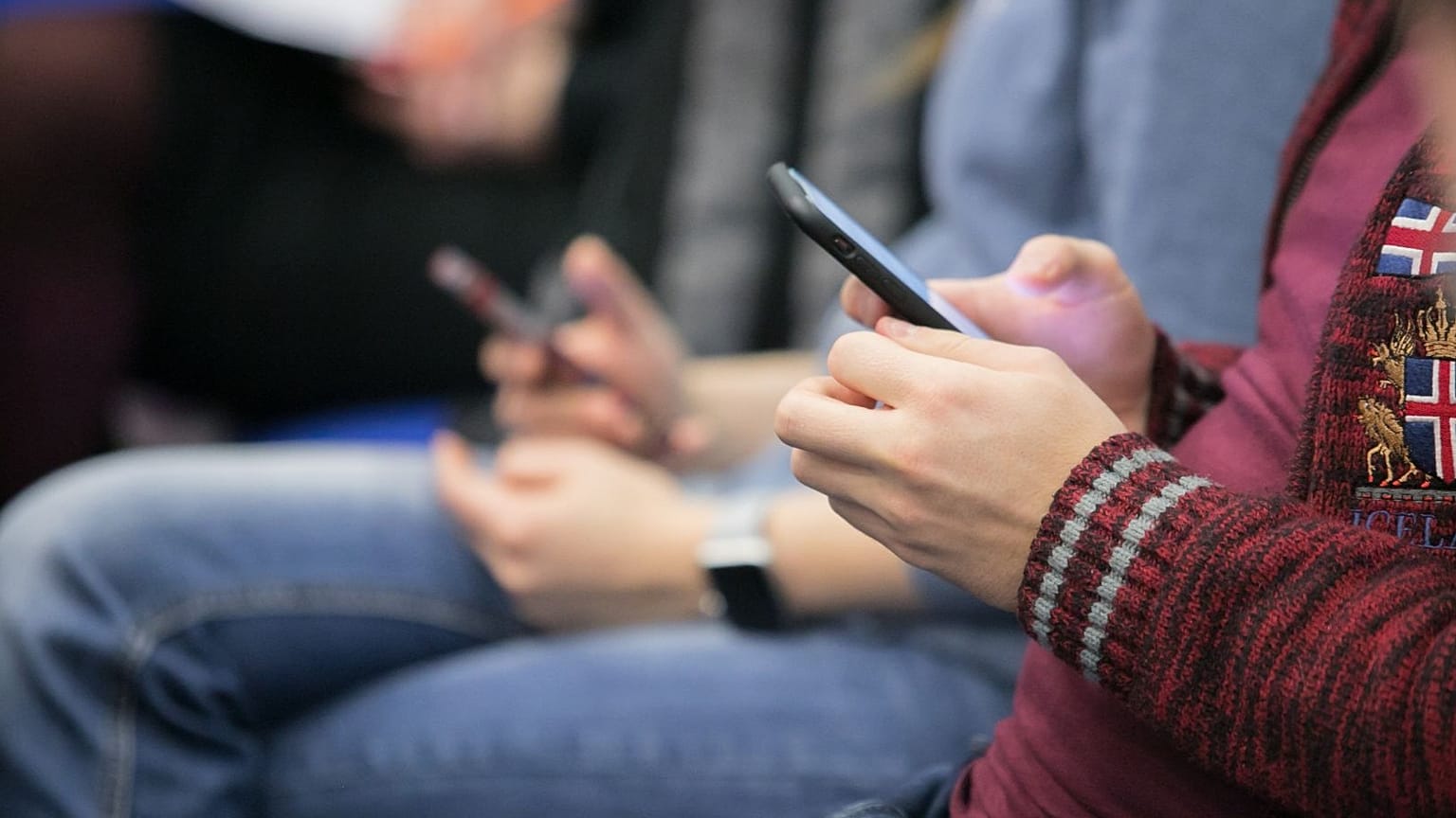 Dos jóvenes con sus teléfonos móviles