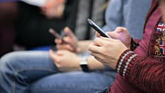 Dos jóvenes con sus teléfonos móviles