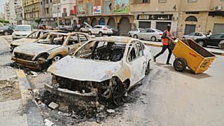 Ağır silahlı milisler arasında çıkan çatışmaların ardından yanmış arabaların yanından geçen bir adam, Trablus, 15 Mayıs 2025.