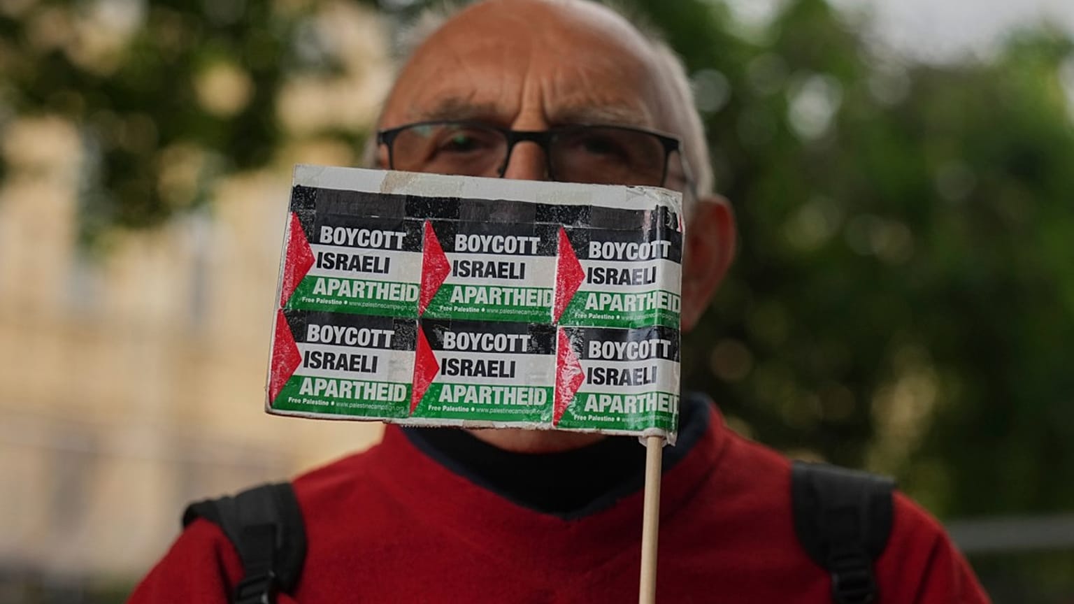 متظاهر مؤيد للفلسطينيين يرفع لافتة في احتجاج خارج مبنى البرلمان خلال أسئلة رئيس الوزراء كير ستارمر في لندن، الأربعاء 4 يونيو 2025. 