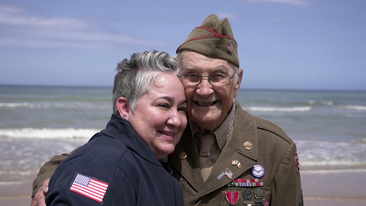 Der Veteran des Zweiten Weltkriegs Wilbur Myers posiert am 2. Juni 2025 bei einem Besuch am Omaha Beach für ein Foto mit einer Frau. Omaha Beach war am 6. Juni 1944 einer der Landungsorte des D-Days.