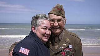 Der Veteran des Zweiten Weltkriegs Wilbur Myers posiert am 2. Juni 2025 bei einem Besuch am Omaha Beach für ein Foto mit einer Frau. Omaha Beach war am 6. Juni 1944 einer der Landungsorte des D-Days.