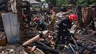 Equipas de salvamento apagam o fogo de uma casa destruída por um ataque de um drone russo em Pryluky, 5 de junho de 2025