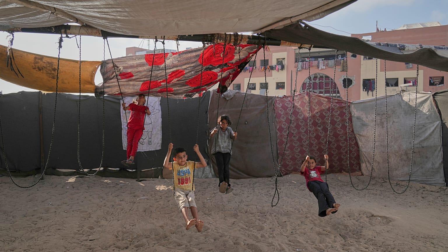 يلعب الأطفال الفلسطينيون النازحون على الأراجيح في مخيم الخيام المؤقت في خان يونس، غزة، يوم الأربعاء، 4 يونيو 2025