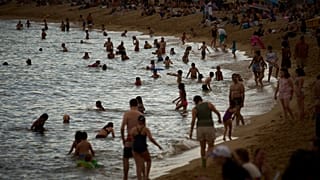 Bañistas se refrescan durante las altas temperaturas en una playa de Barcelona, España, el sábado 31 de mayo de 2025.