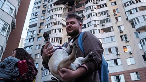 Un homme porte son chien devant un immeuble résidentiel endommagé après une attaque de drone russe sur Kyiv, en Ukraine, le vendredi 6 juin 2025