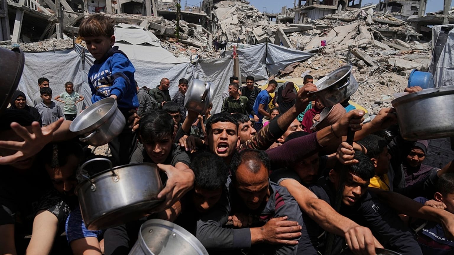 فلسطينيون يحاولون الحصول على مساعدات غذائية في مطبخ مجتمعي ببيت لاهيا شمال قطاع غزة، 3 أيار/مايو 2025.