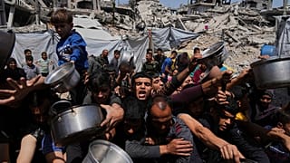 فلسطينيون يحاولون الحصول على مساعدات غذائية في مطبخ مجتمعي ببيت لاهيا شمال قطاع غزة، 3 أيار/مايو 2025.