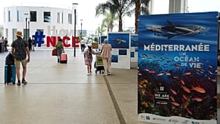 As pessoas saem do aeroporto junto a sinais que antecedem a próxima Conferência das Nações Unidas sobre os Oceanos, em Nice.