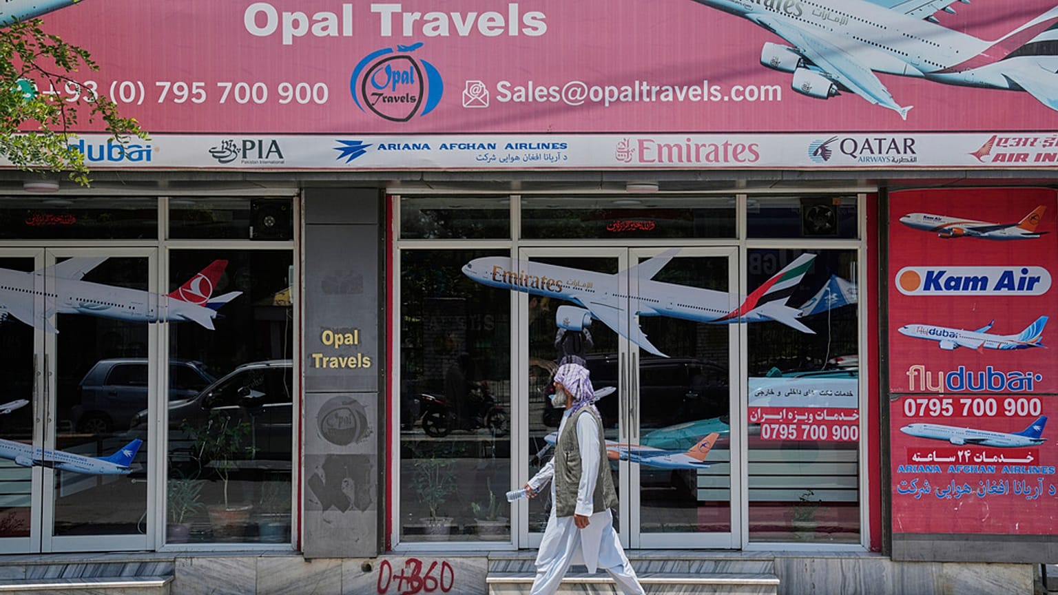 An Afghan person passes in front of an air travel agency in Kabul, Afghanistan.