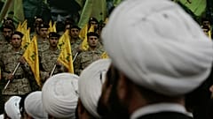 رجال دين شيعة لبنانيون يجلسون أمام مقاتلي حزب الله أثناء مشاركتهم في تجمع إحياءً لذكرى القائد العسكري البارز في حزب الله عماد مغنية، يوم الجمعة 22 فبراير/شباط 2008. 