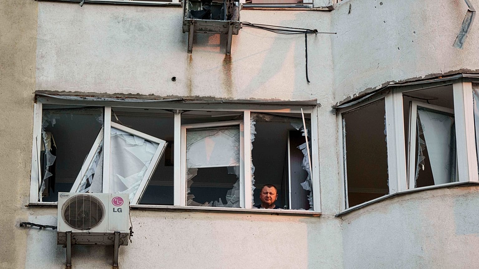 Un uomo guarda dalla finestra di un edificio residenziale a più piani danneggiato dopo l'attacco di un drone russo a Kiev, in Ucraina, venerdì 6 giugno 2025. (Foto AP/Evgeniy Maloletka)