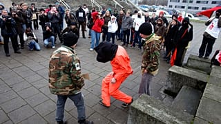 DOSSIER : Des manifestants, dont l'un porte une combinaison de prisonnier style Guantanamo Bay, se rassemblent lors de la visite du président américain George W. Bush à Tallinn, en Estonie, le mardi 28 novembre 200.