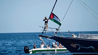 ناشطة المناخ غريتا ثونبرغ تقف بالقرب من علم فلسطيني بعد صعودها على متن السفينة مادلين وقبل الإبحار إلى غزة برفقة نشطاء يوم الأحد 1 يونيو 2025