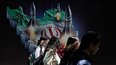 Iranische Frauen gehen an einem Transparent vorbei, das den Abschuss von Raketen von der iranischen Landkarte im Norden Teherans zeigt, 19. April 2024