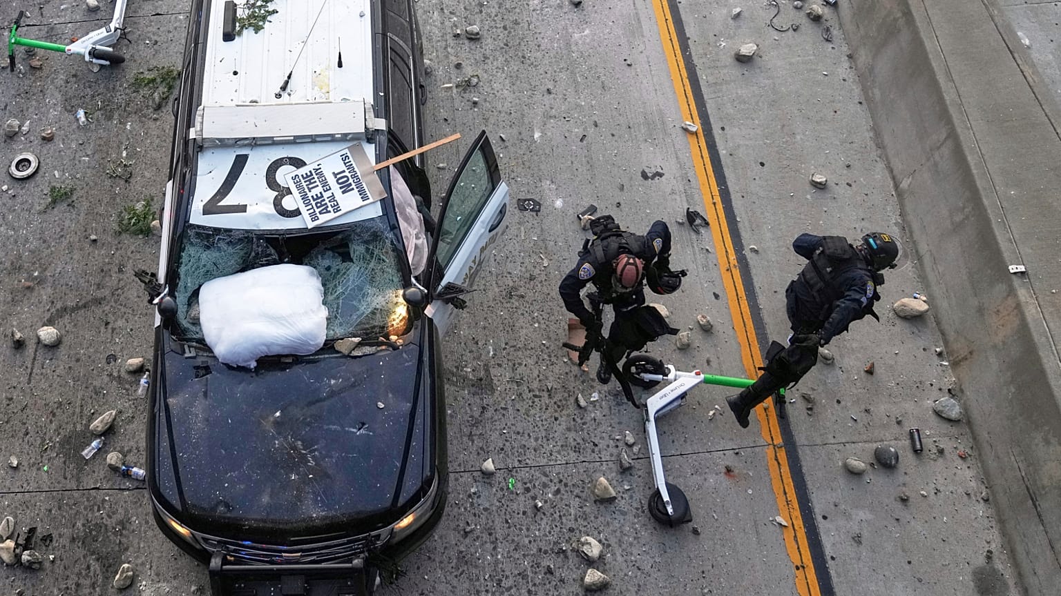 Dos agentes de la Patrulla de Carreteras de California intentan esquivar piedras cerca del Centro de Detención Metropolitano en Los Ángeles, el domingo 8 de junio de 2025
