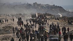 فلسطينيون نازحون يمرون بجانب أنقاض مبانٍ مدمرة على طول ساحل مدينة غزة يوم الإثنين، 9 يونيو 2025