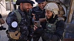 عنصر من الأمن السوري يضحك مع عناصر من قوات سوريا الديمقراطية على أطراف الشيخ مقصود في حلب 2 يونيو / حزيران 2025