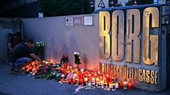Ein Mann stellt eine Kerze am Eingang einer Schule auf, nachdem dort eine tödliche Schießerei stattgefunden hat, in Graz, Österreich, Dienstag, 10. Juni 2025
