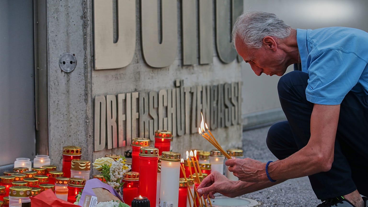 Un homme allume des bougies à l'entrée d'une école, après une fusillade mortelle, à Graz, en Autriche, mardi 10 juin 2025