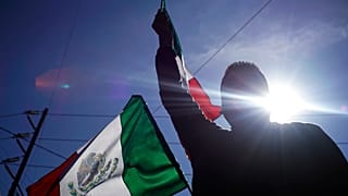 متظاهر يلوح بعلم مكسيكي خارج مأوى للمهاجرين احتجاجًا على وجود آلاف المهاجرين من أمريكا الوسطى في تيخوانا، المكسيك
