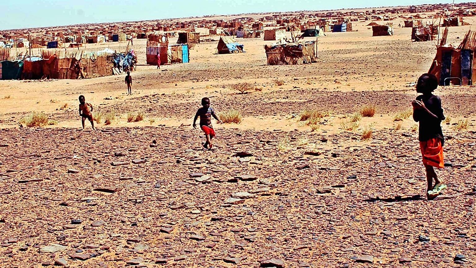أطفال يتجولون في مخيم الفاتح للنازحين، على بُعد 38 كيلومترًا (24 ميلًا) من العاصمة السودانية الخرطوم، يوم الاثنين 21 مارس/آذار 2005.  