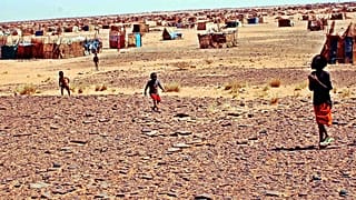 أطفال يتجولون في مخيم الفاتح للنازحين، على بُعد 38 كيلومترًا (24 ميلًا) من العاصمة السودانية الخرطوم، يوم الاثنين 21 مارس/آذار 2005.  