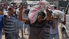  فلسطيني يحمل حقيبة تحتوي على طعام ومساعدات إنسانية، في رفح، جنوب قطاع غزة، الأربعاء 11 يونيو/حزيران 2025.  