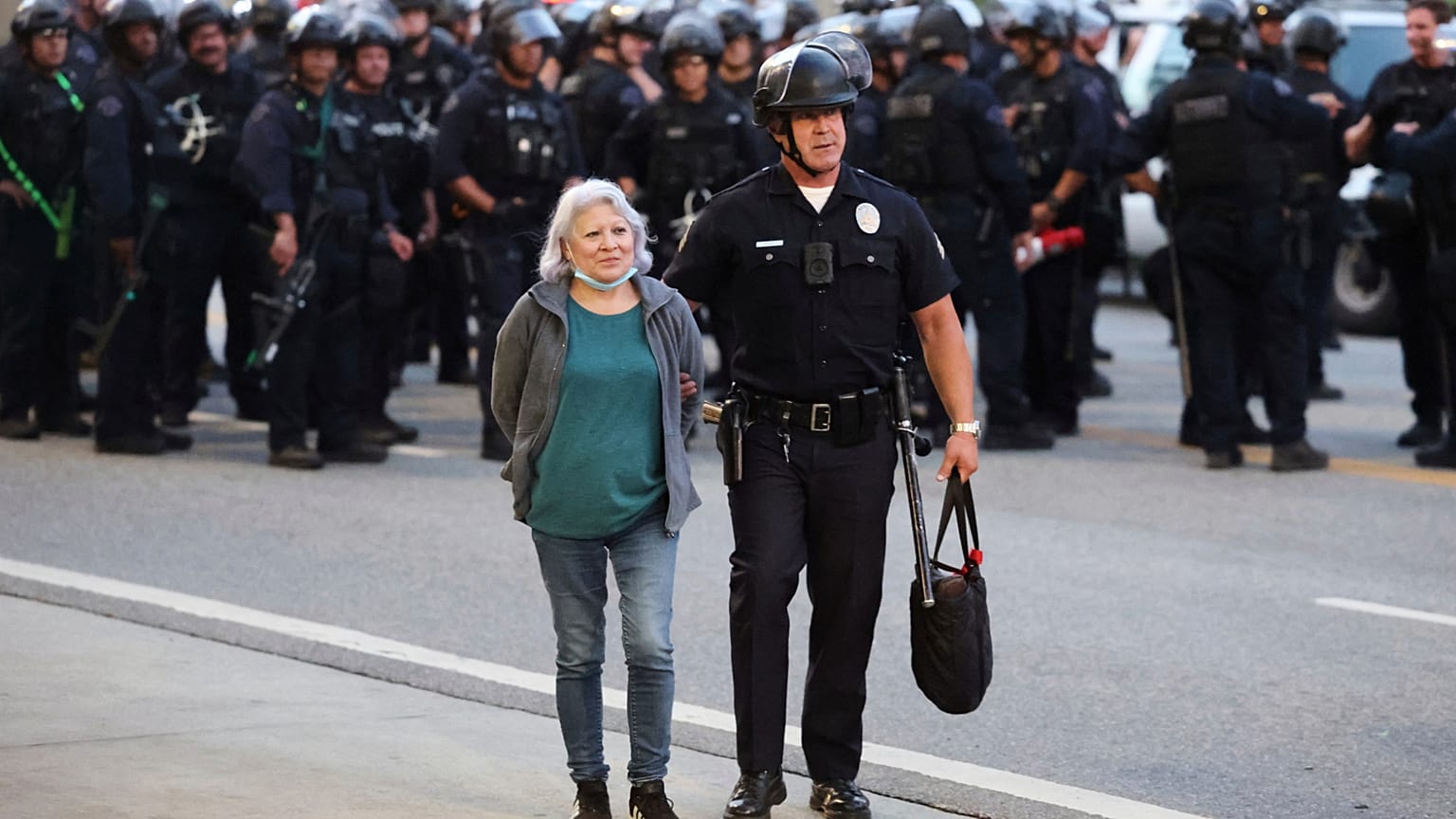 Un agente de la ley escolta a una mujer fuera de una protesta después de ser detenida el miércoles 11 de junio de 2025, en Los Ángeles
