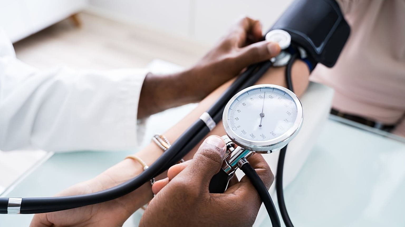 Um médico verifica a tensão arterial de um doente.
