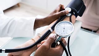 Um médico verifica a tensão arterial de um doente.