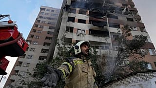 رجل إطفاء يستدعي زملائه في موقع انفجار في مجمع سكني في شمال طهران، إيران، الجمعة 13 يونيو/حزيران 2025.  