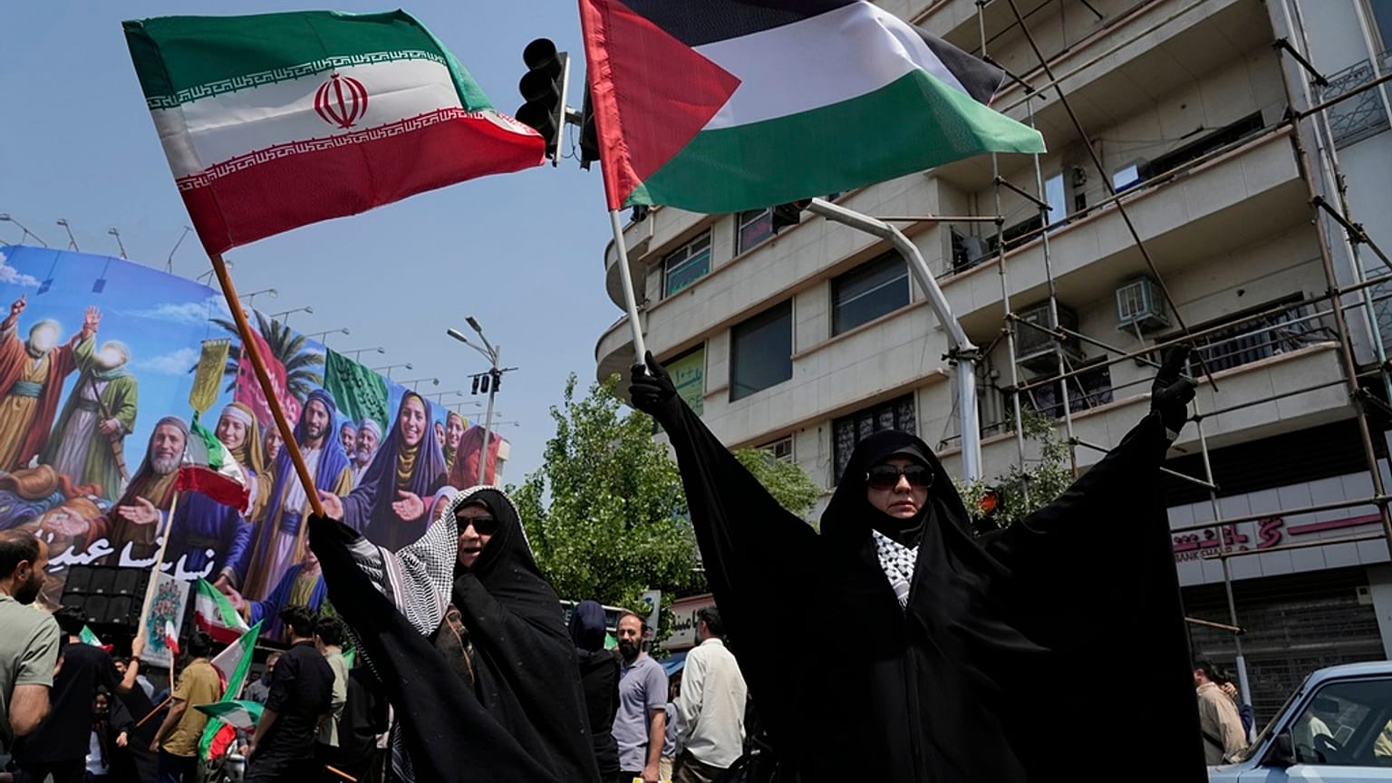 متظاهرون إيرانيون يرفعون الأعلام الإيرانية والفلسطينية في تجمع مناهض لإسرائيل في طهران، إيران، الجمعة 13 يونيو/حزيران 2025. 