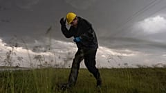 Joey Toniolo se agacha ante la caída de granizo mientras retrocede hacia el vehículo durante una operación del Proyecto ICECHIP, el 6 de junio de 2025, en Morton, Texas.