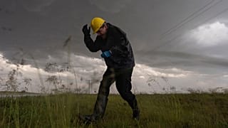 Joey Toniolo se agacha ante la caída de granizo mientras retrocede hacia el vehículo durante una operación del Proyecto ICECHIP, el 6 de junio de 2025, en Morton, Texas.