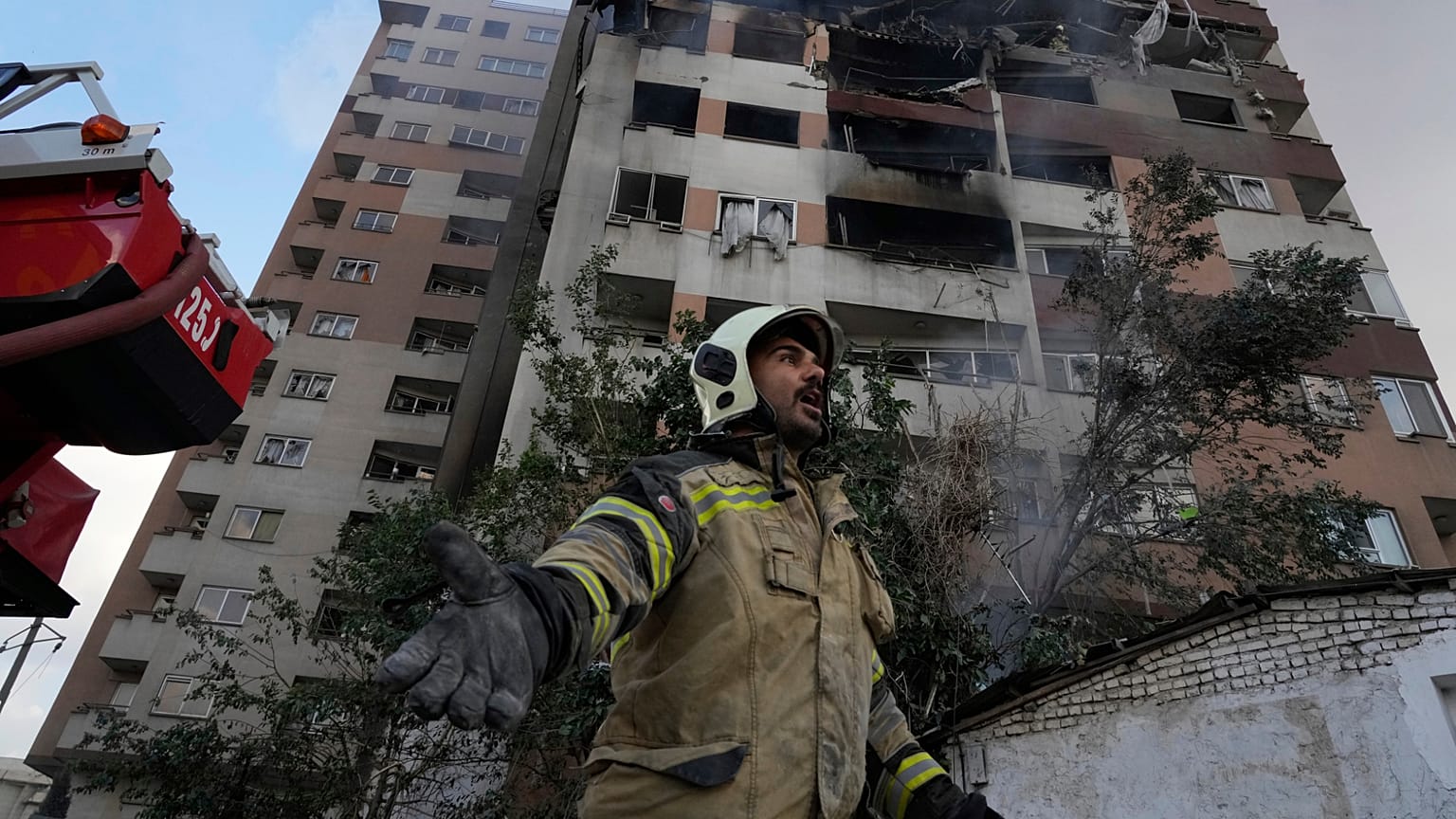 رجل إطفاء ينادي زملاءه في موقع انفجار في مجمع سكني في شمال طهران، إيران، الجمعة 13 يونيو 2025