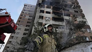 Tahran'da bir itfaiye görevlisi, İsrail saldırısından sonra yangın söndürme çalışmalarında.