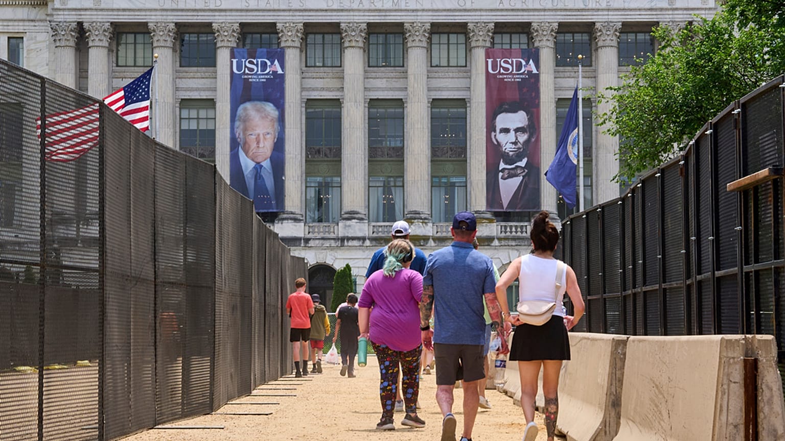 Le persone camminano tra le recinzioni di sicurezza e le barricate di cemento verso una grande fotografia del presidente Donald Trump e del presidente Abraham Lincoln, venerdì 13 giugno 2025.