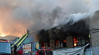 Bir kurtarma görevlisi, 14 Haziran 2025 Cumartesi günü Ukrayna'nın Zaporijya kentinde Rus insansız hava aracının saldırısı sonucu tahrip olan insani yardım deposunda çıkan yangını söndürüyor.