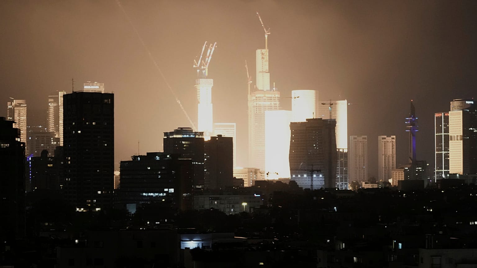 İsrail'in Tel Aviv kentinde 14 Haziran 2025, Cumartesi günü erken saatlerde bir mermi saldırısının neden olduğu patlama ufuk çizgisini aydınlatıyor