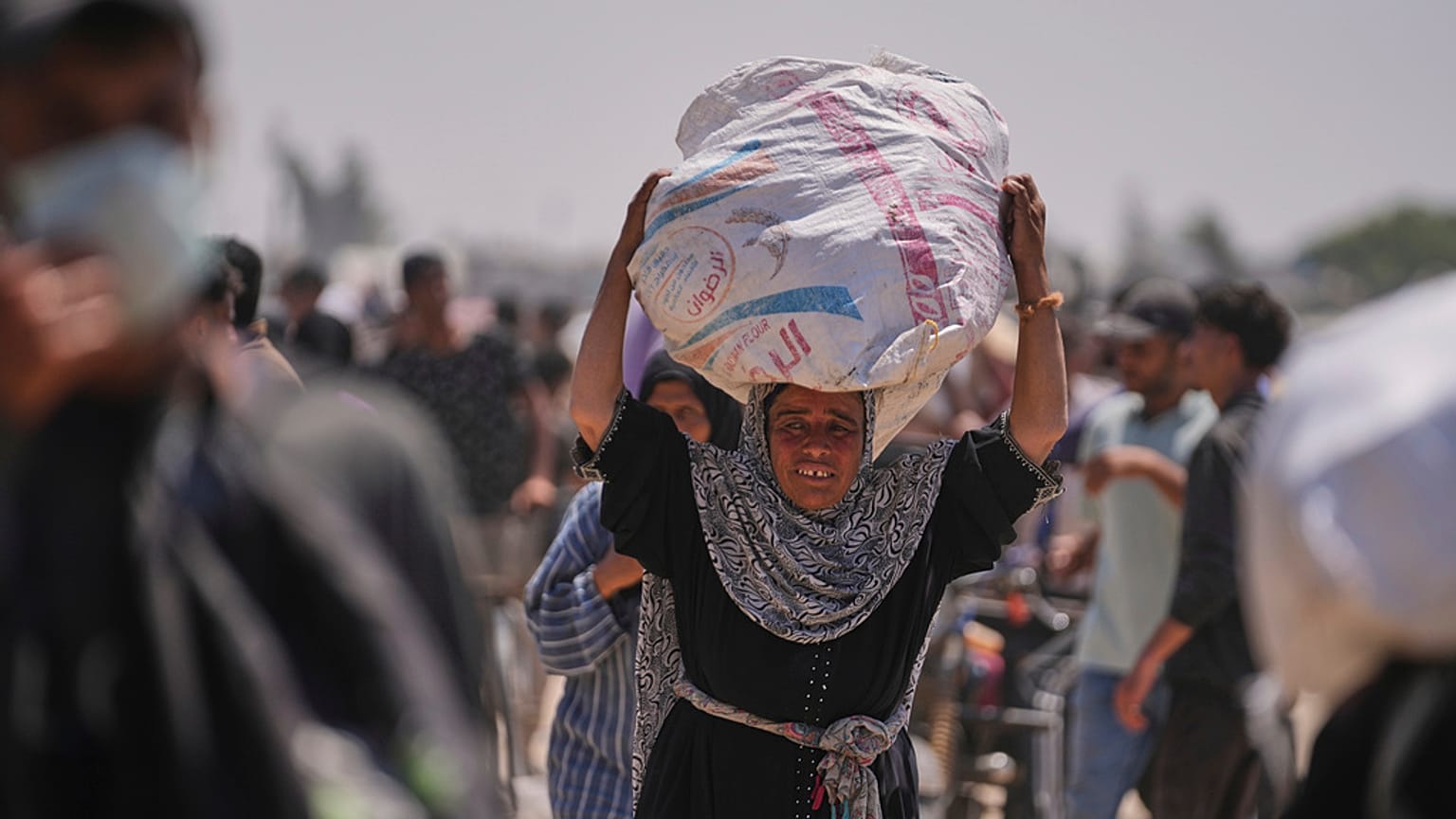 امرأة فلسطينية تحمل حقيبة تحتوي على مواد غذائية ومساعدات إنسانية سلمتها مؤسسة غزة الإنسانية، وهي منظمة مدعومة من الولايات المتحدة، في رفح، جنوب غزة، الأربعاء، 11 يونيو 2025