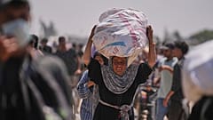 امرأة فلسطينية تحمل حقيبة تحتوي على مواد غذائية ومساعدات إنسانية سلمتها مؤسسة غزة الإنسانية، وهي منظمة مدعومة من الولايات المتحدة، في رفح، جنوب غزة، الأربعاء، 11 يونيو 2025