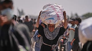 امرأة فلسطينية تحمل حقيبة تحتوي على مواد غذائية ومساعدات إنسانية سلمتها مؤسسة غزة الإنسانية، وهي منظمة مدعومة من الولايات المتحدة، في رفح، جنوب غزة، الأربعاء، 11 يونيو 2025